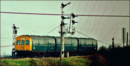 DMU comes past a signal at March South Junction in BR days