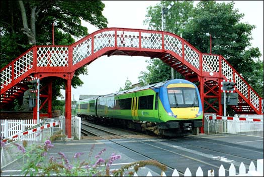 Central Trains class 170 comes under the footbridge and over the level crossing in 2003 