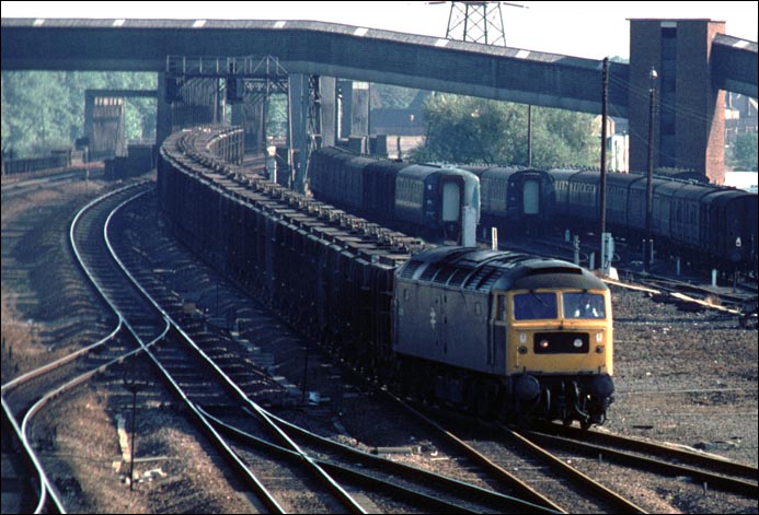 A class 47 with a fly-ash train on the down slow has just crossed the River Nene 