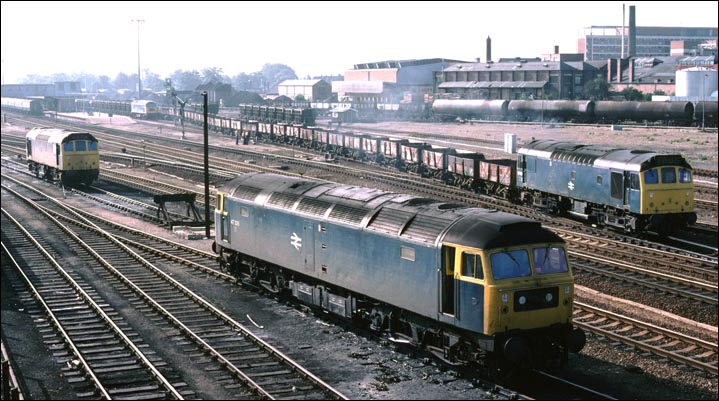 A Class 25 brings on a long freight of open wagons comes out of the goods loops near the station.